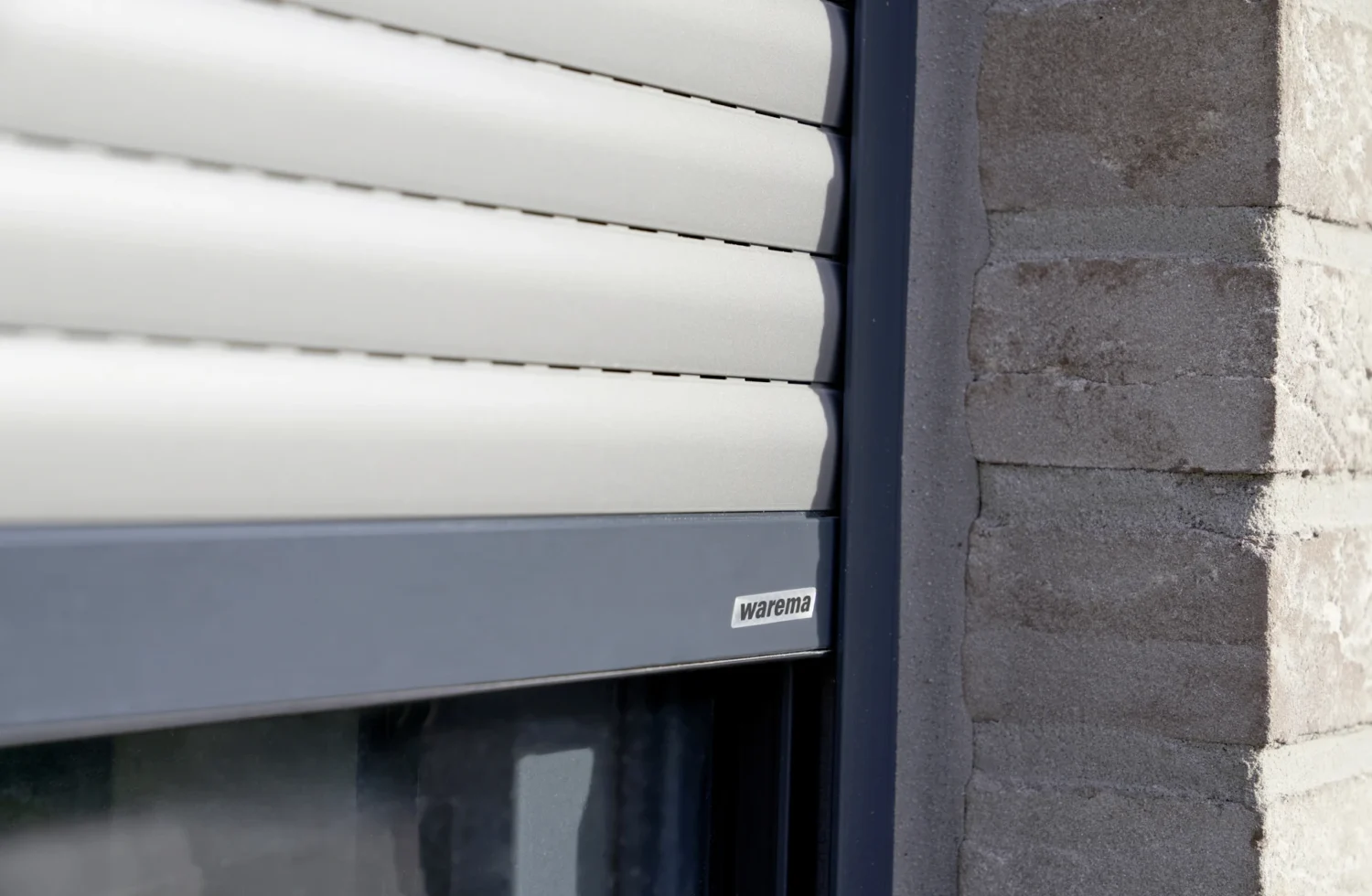 Nahaufnahme eines modernen Rollladens von Warema an einem Ziegelgebäude