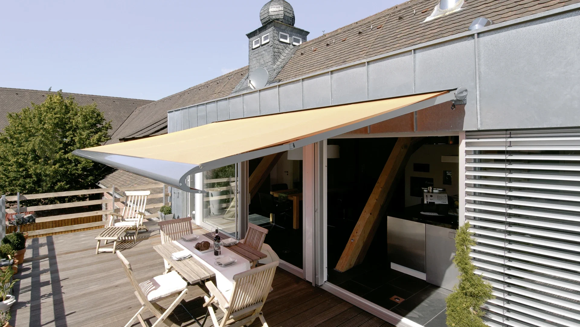 Terrasse mit Markise und Gartenmöbeln an einem sonnigen Tag